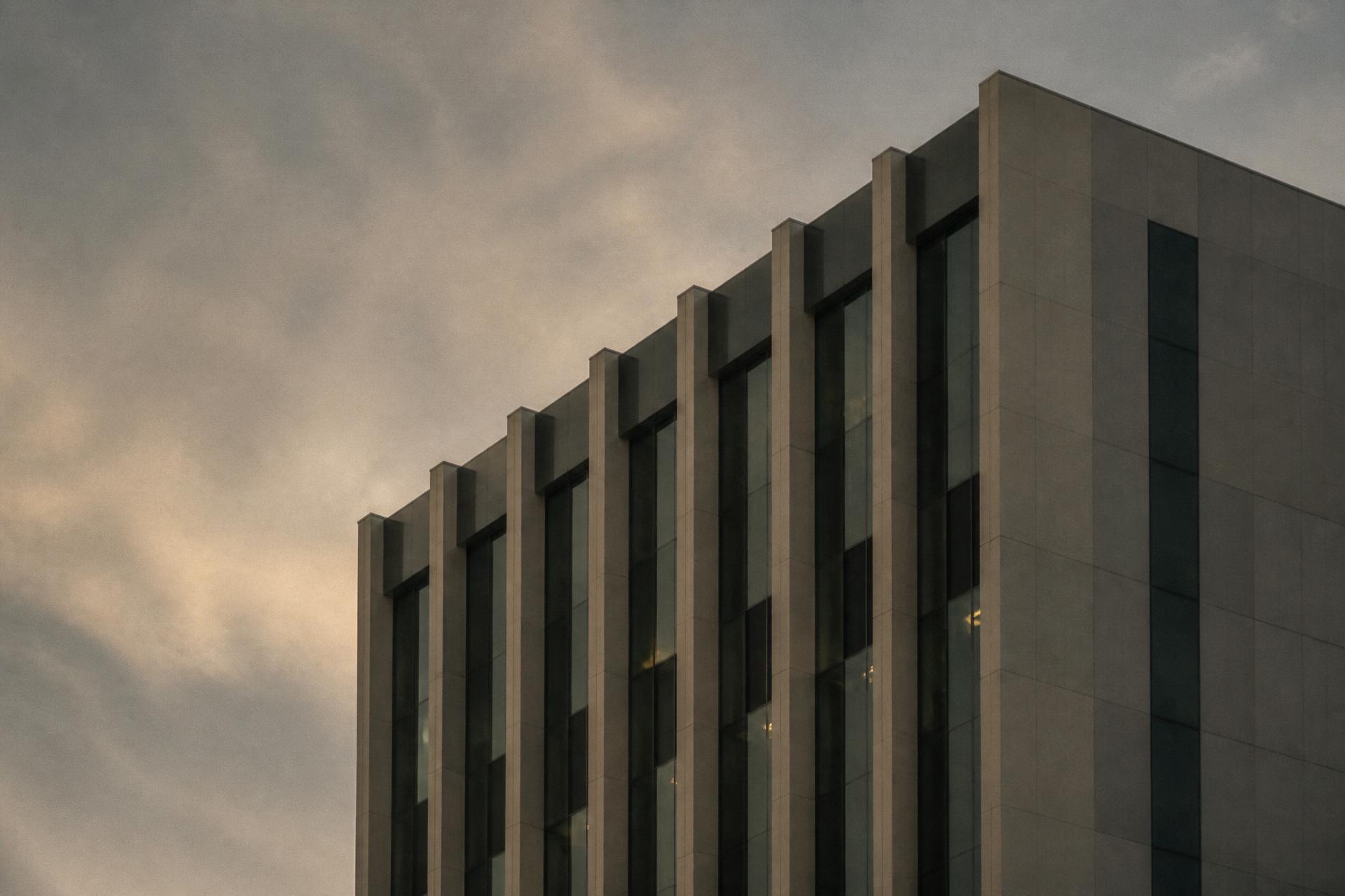 Fachada de edifício concluído em concreto e vidro sob céu encoberto