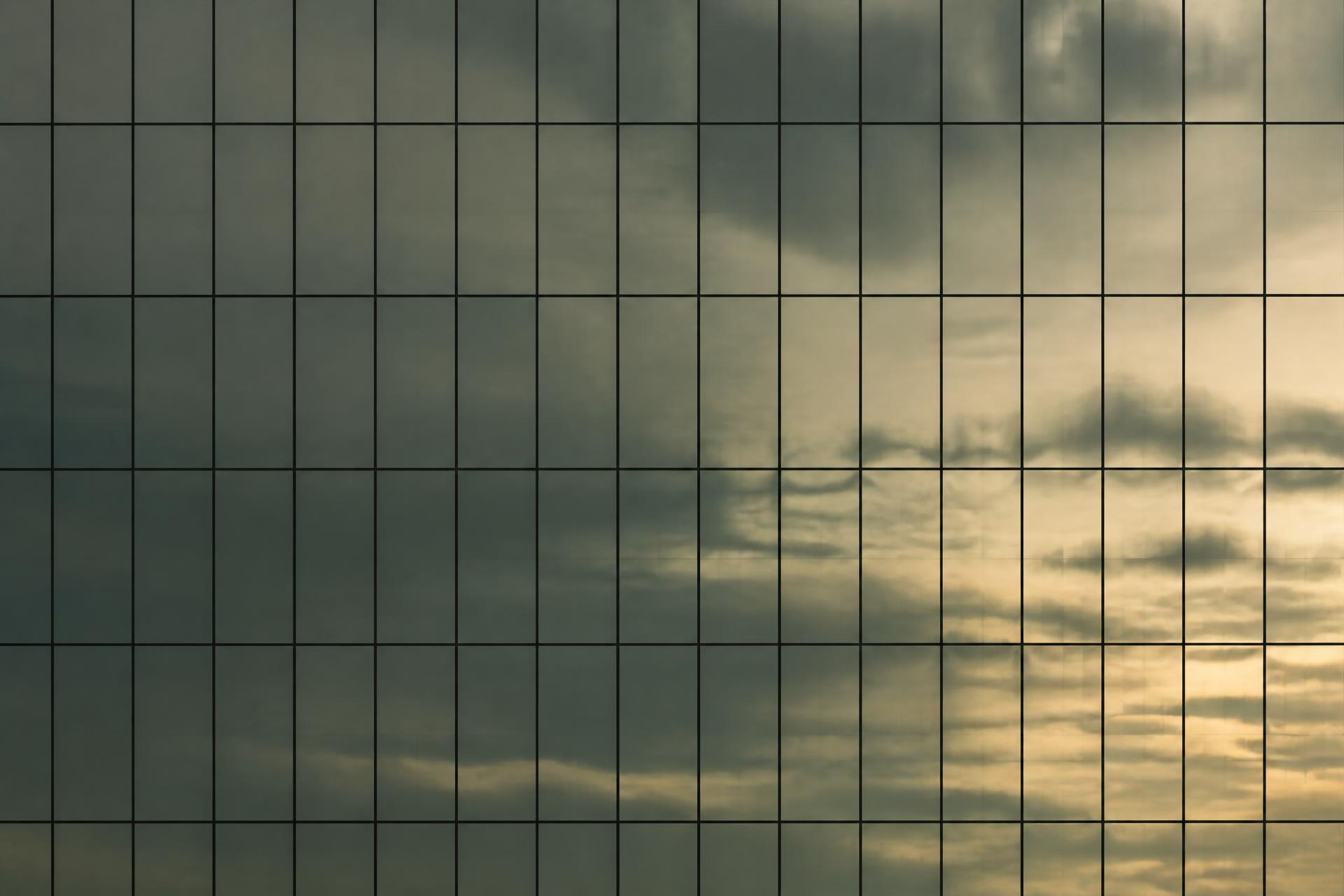 Reflexo do céu em camadas sobre fachada de vidro, sem o entorno no quadro